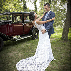 Krystal en déséquilibre arriere enlacée par son mari Aurélien devant une vieille voiture rouge au lac d'Ardres