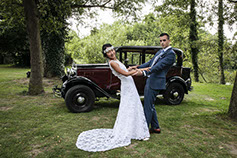 LES MARIES SONT FACE 0 FACE DEVANT LA VIEILLE VOITURE DU MARIAGE