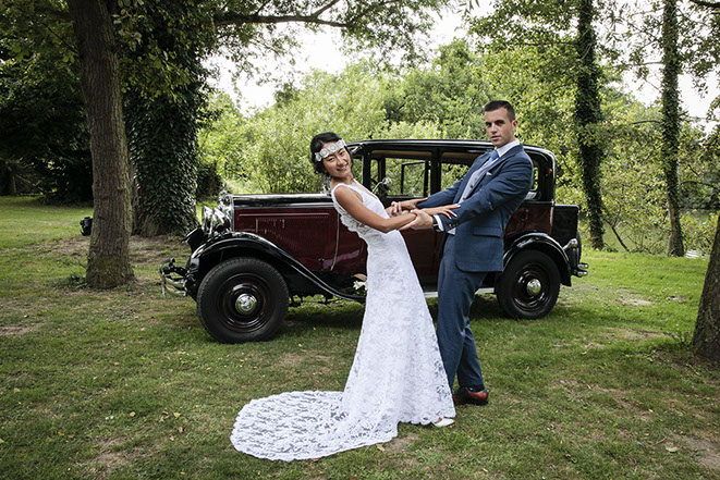 LES MARIES SONT FACE 0 FACE DEVANT LA VIEILLE VOITURE DU MARIAGE