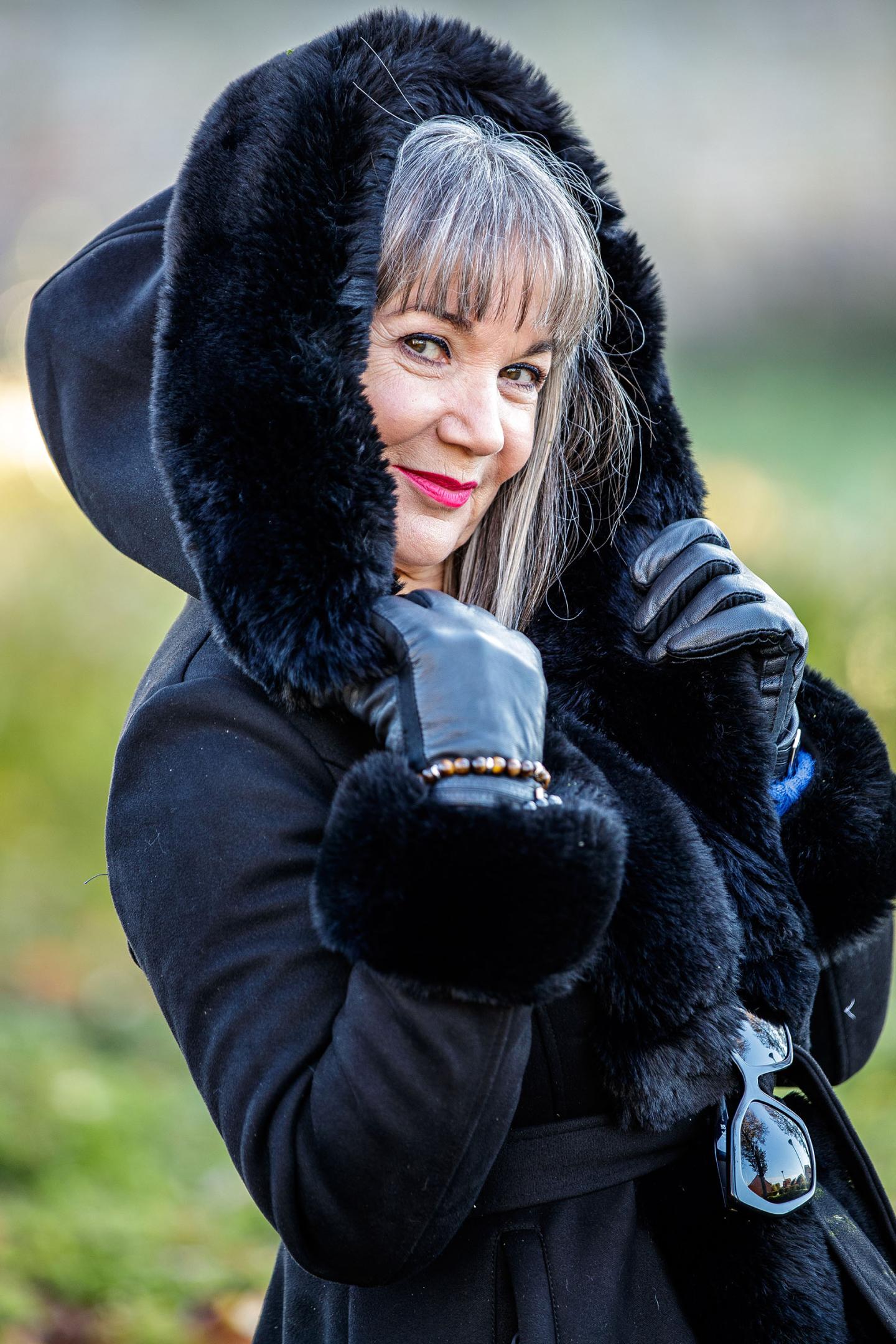 SOMAIN-100 a woman wearing a black coat with a fur hood